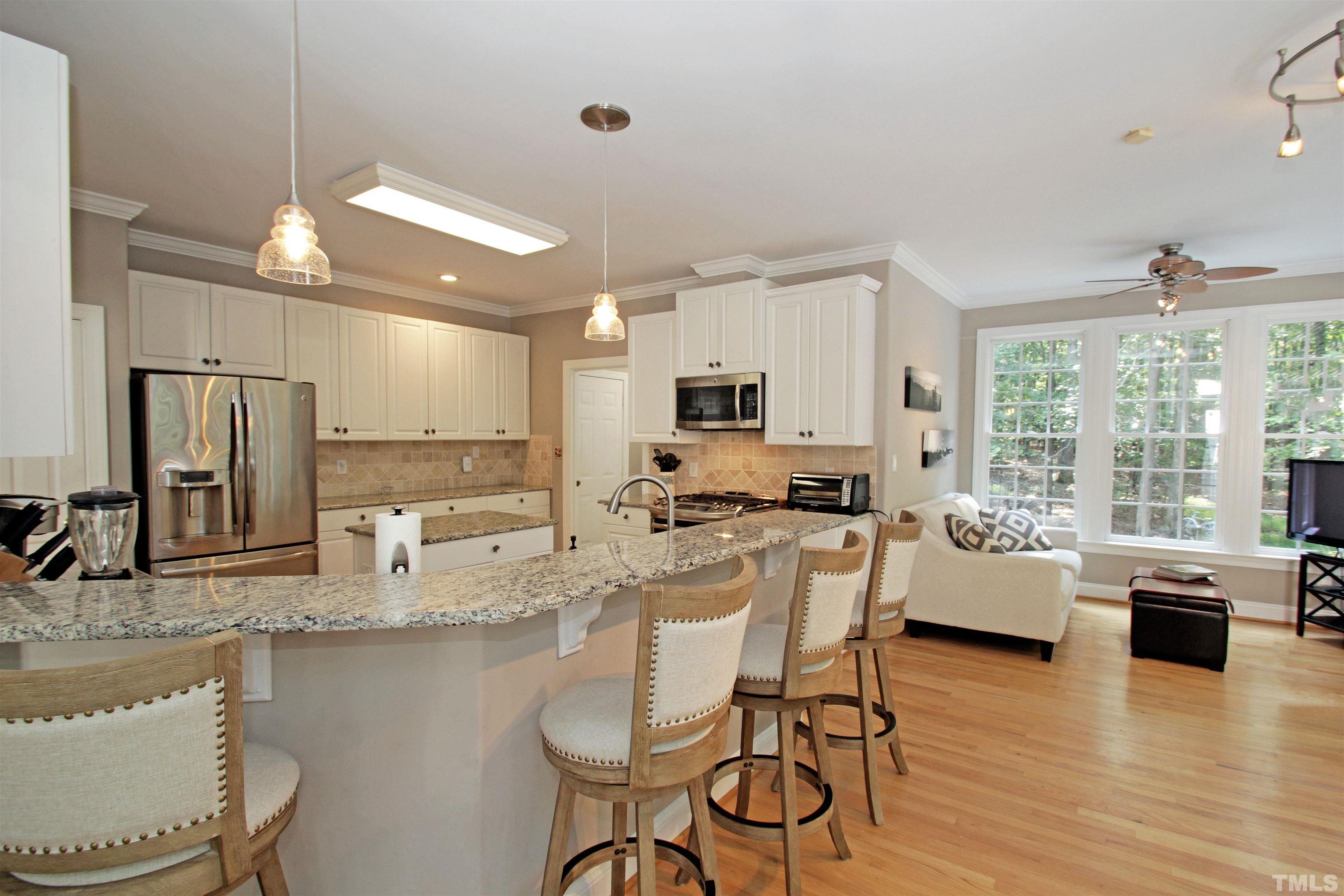 11817 Mountbatten Way Raleigh, NC 27613 - Photo 5 of 28 a kitchen with stainless steel appliances granite countertop a stove top oven a sink dishwasher a dining table and chairs with wooden floor