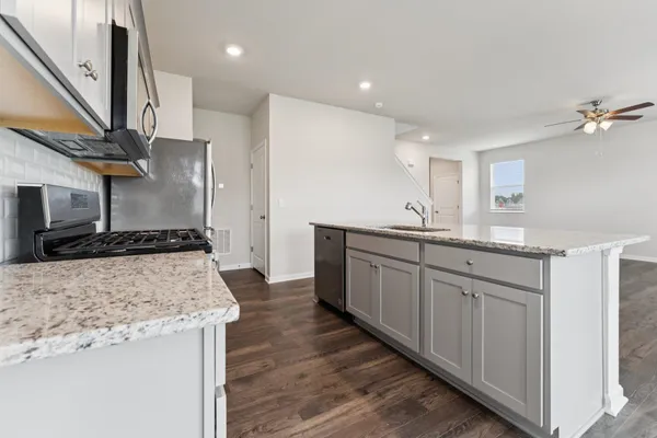 a kitchen with stainless steel appliances granite countertop a sink a stove and a wooden floors
