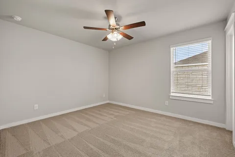 an empty room with a window and a fan