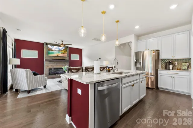 a kitchen with stainless steel appliances granite countertop a stove top oven a sink dishwasher and a refrigerator with wooden floor