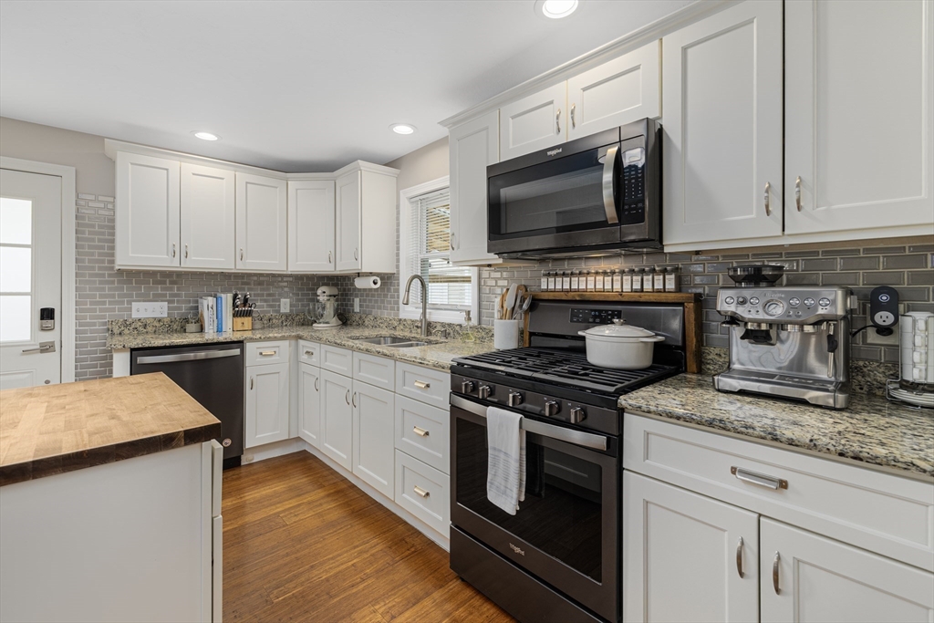 69 Denver Street Fall River, MA 02721 - Photo 13 of 35 a kitchen with granite countertop a stove top oven a sink dishwasher and white cabinets with wooden floor