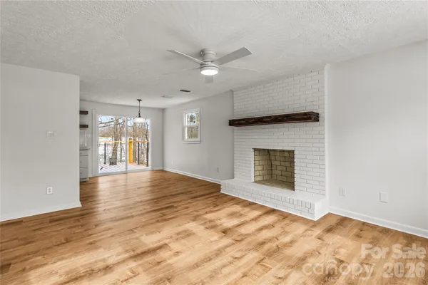 a view of an empty room with a fireplace and a window
