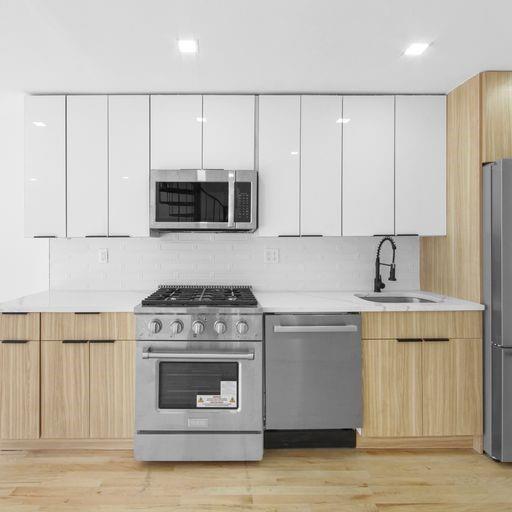 87 Adelphi Street Brooklyn, NY 11205 - Photo 24 of 35 a kitchen with stainless steel appliances a stove a microwave a sink and cabinets