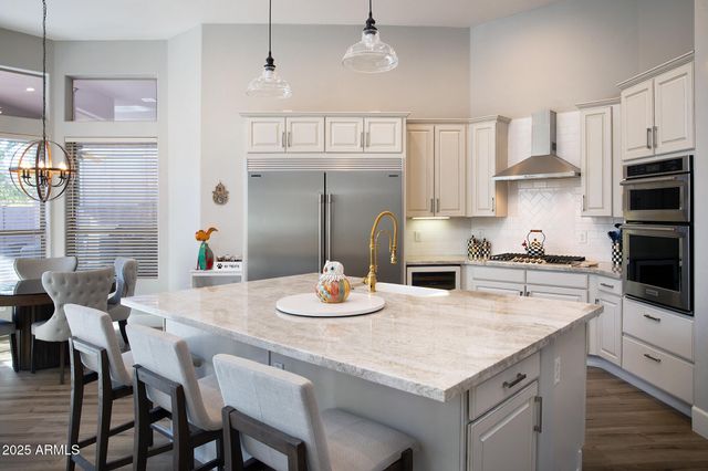a kitchen with stainless steel appliances kitchen island granite countertop a table chairs stove and white cabinets