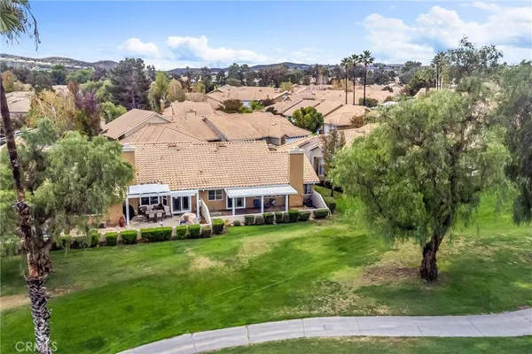 a view of a house with a big yard and large trees