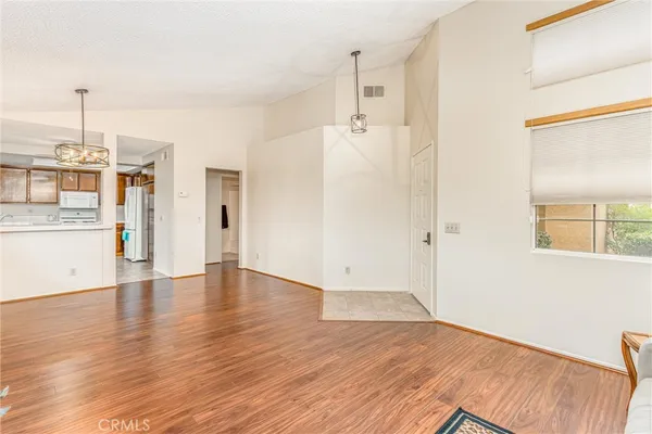 a view of a kitchen with a fridge and wooden floor