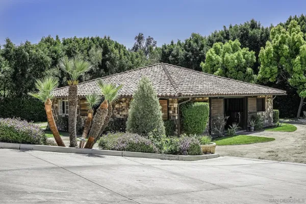 a view of a patio with table and chairs under an umbrella with large trees