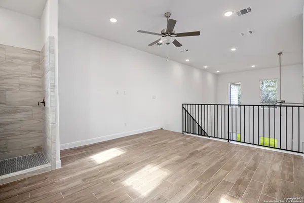 an empty room with wooden floor fan and windows