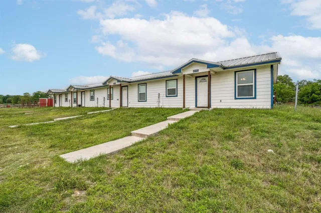 a view of a house with a big yard and large trees