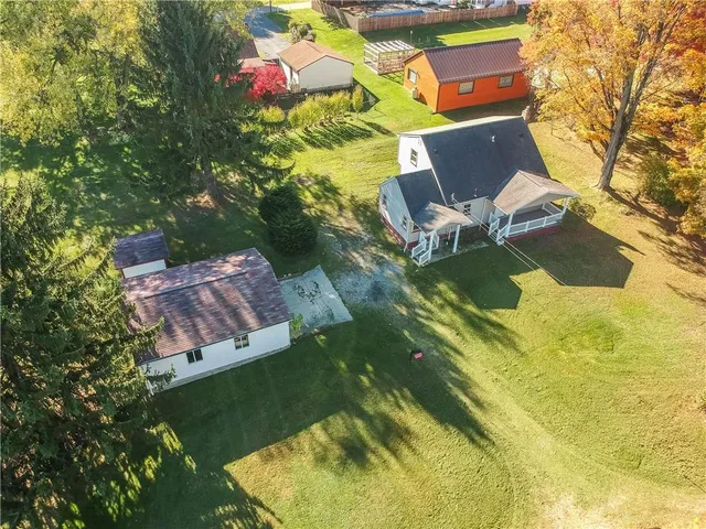 an aerial view of a house with swimming pool and large trees