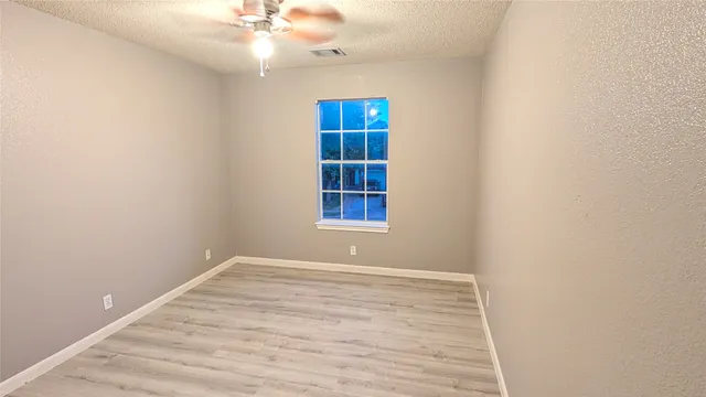 an empty room with a ceiling fan and window