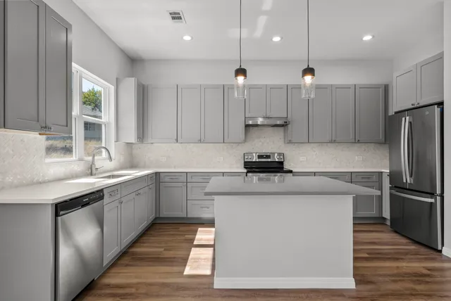 a kitchen with a sink stainless steel appliances and windows