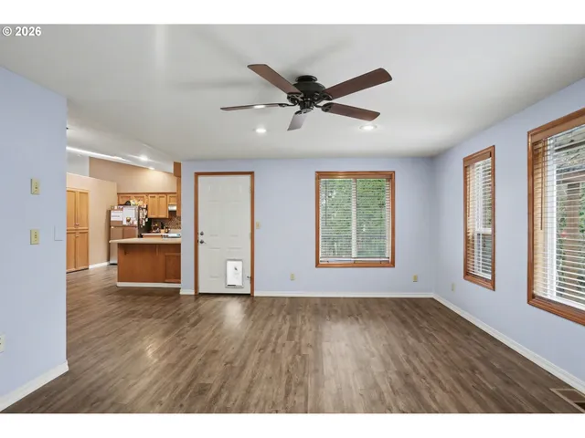 a view of an empty room with a window and wooden floor