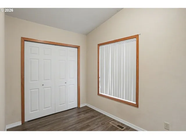 a view of an empty room with closet and a window