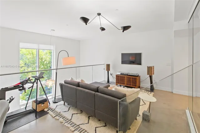 a living room with furniture a flat screen tv and a large window