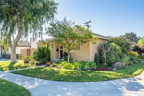a front view of a house with a yard and potted plants