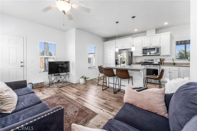 a kitchen with stainless steel appliances granite countertop a stove top oven a refrigerator a kitchen island and chairs with wooden floor