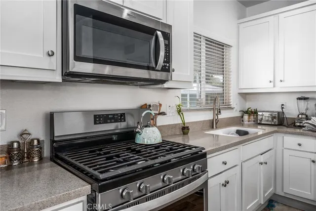 a kitchen with stainless steel appliances a stove a sink cabinets and a refrigerator