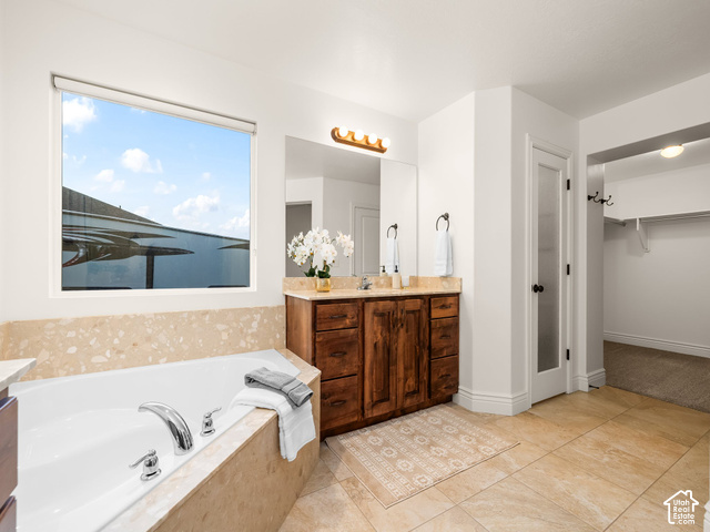 1288 North Horizon View Loop Elk Ridge, UT 84651 - Photo 13 of 38 Built-in soaking tub with polished chrome fixtures, dual vanity with wood cabinetry and stone countertop, large window, and tiled flooring
