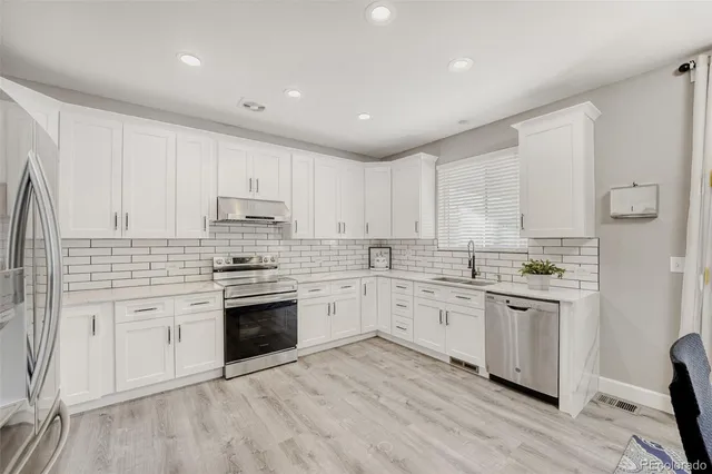 a kitchen with granite countertop white cabinets and stainless steel appliances