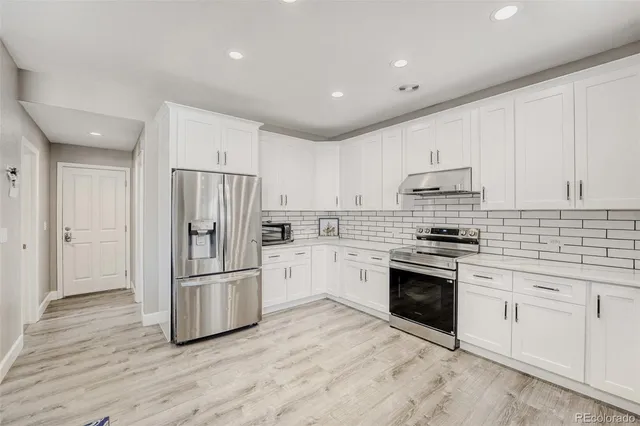 a kitchen with granite countertop white cabinets and stainless steel appliances
