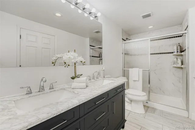 a bathroom with a granite countertop sink a toilet and shower