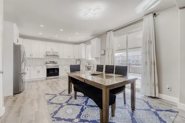 a room with stainless steel appliances kitchen island granite countertop a table chairs and a refrigerator