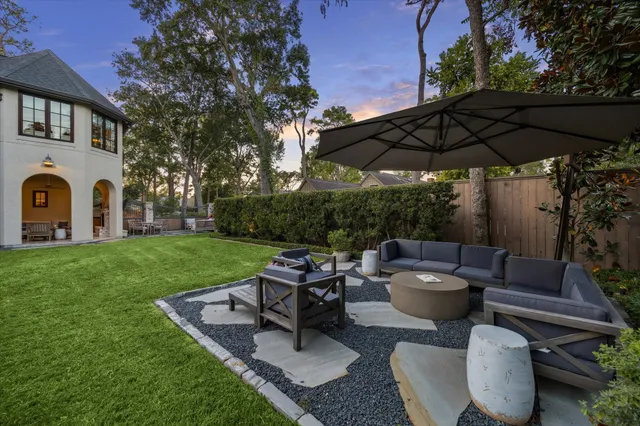a view of a patio with couches table and chairs under an umbrella