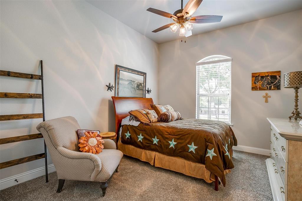 409 Glade Crest Road Azle, TX 76020 - Photo 21 of 31 a bedroom with a bed and a chandelier