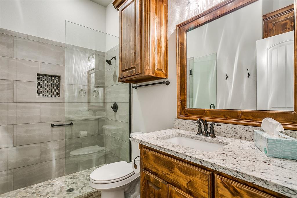 409 Glade Crest Road Azle, TX 76020 - Photo 24 of 31 a bathroom with a granite countertop sink a toilet and shower