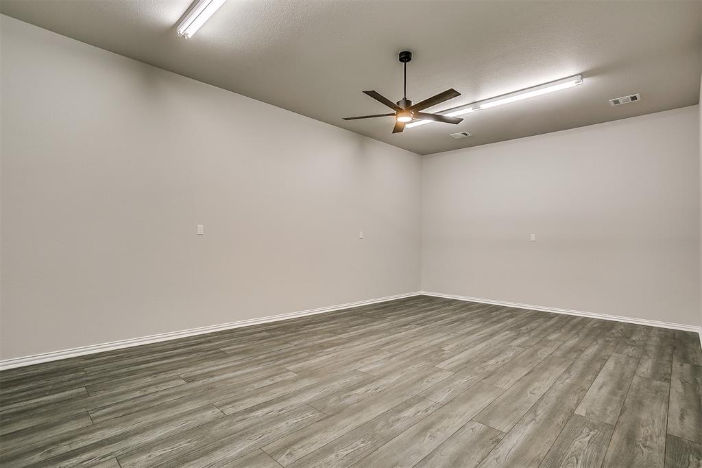 409 Glade Crest Road Azle, TX 76020 - Photo 27 of 31 an empty room with wooden floor fan and windows