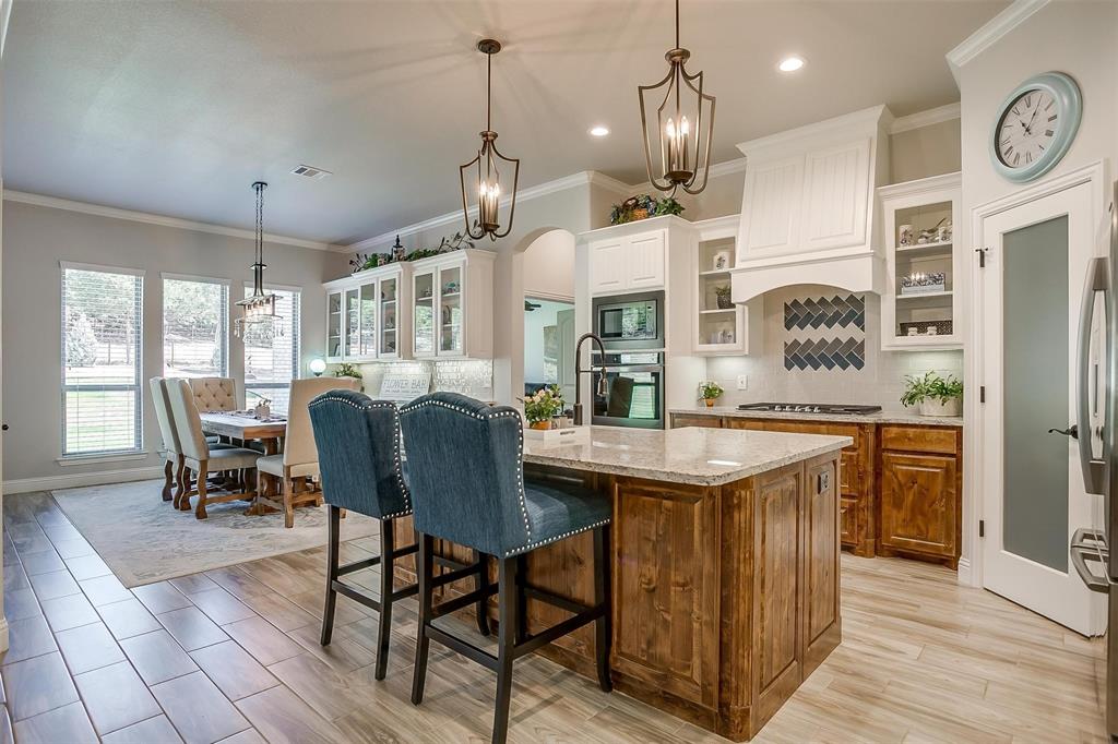409 Glade Crest Road Azle, TX 76020 - Photo 8 of 31 a open kitchen with stainless steel appliances granite countertop a stove top oven a refrigerator a dining table and chairs with wooden floor