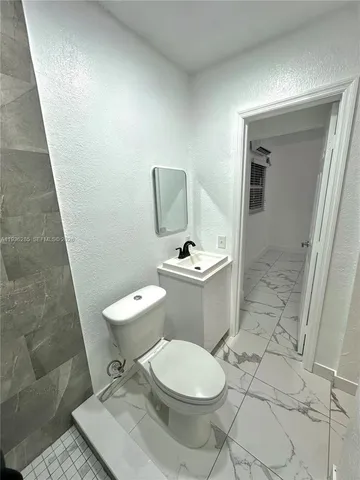a white toilet sitting next to a bathroom sink and a mirror