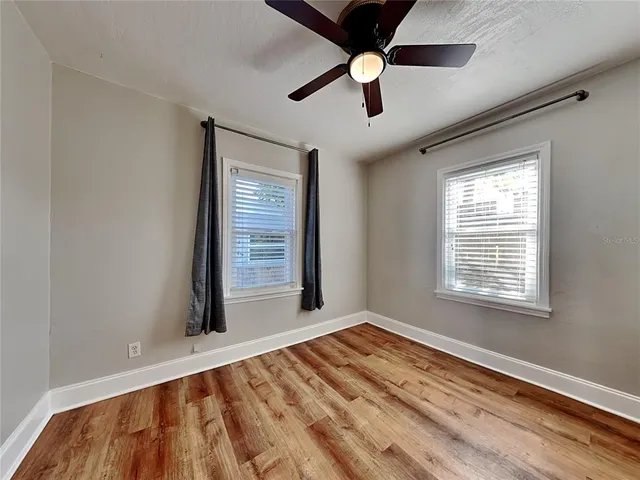 a view of an empty room with a window and wooden floor