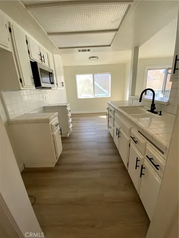 a large white kitchen with wooden floor and stainless steel appliances