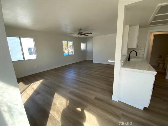 a kitchen view with wooden floor and ceiling fan