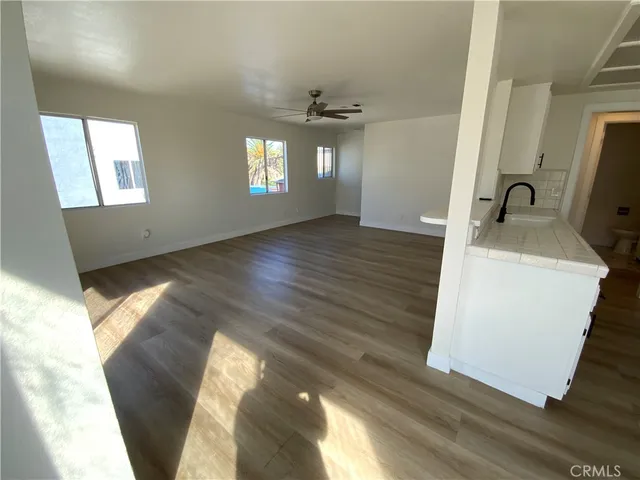 a view of empty room with wooden floor and fan