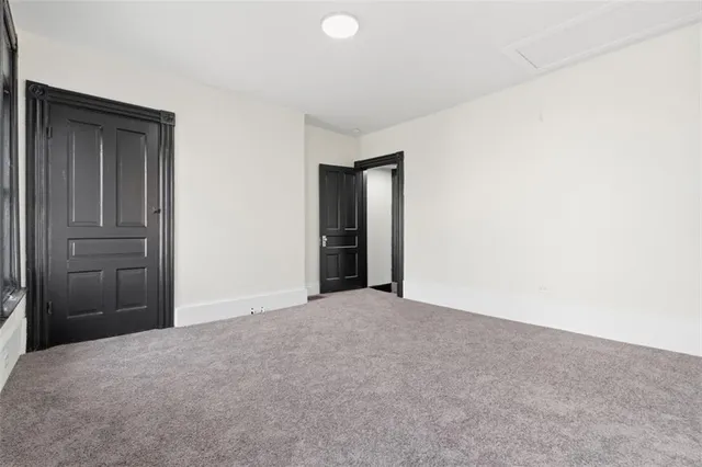 a view of an empty room with closet and bathroom