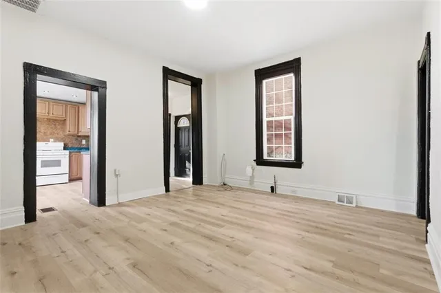 a view of an empty room with window and hardwood floor