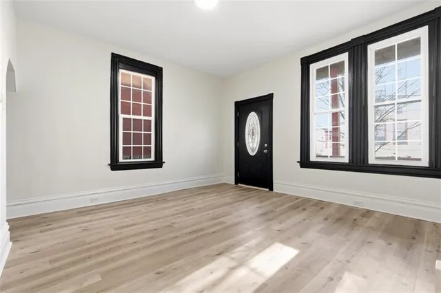 a view of an empty room with window and wooden floor