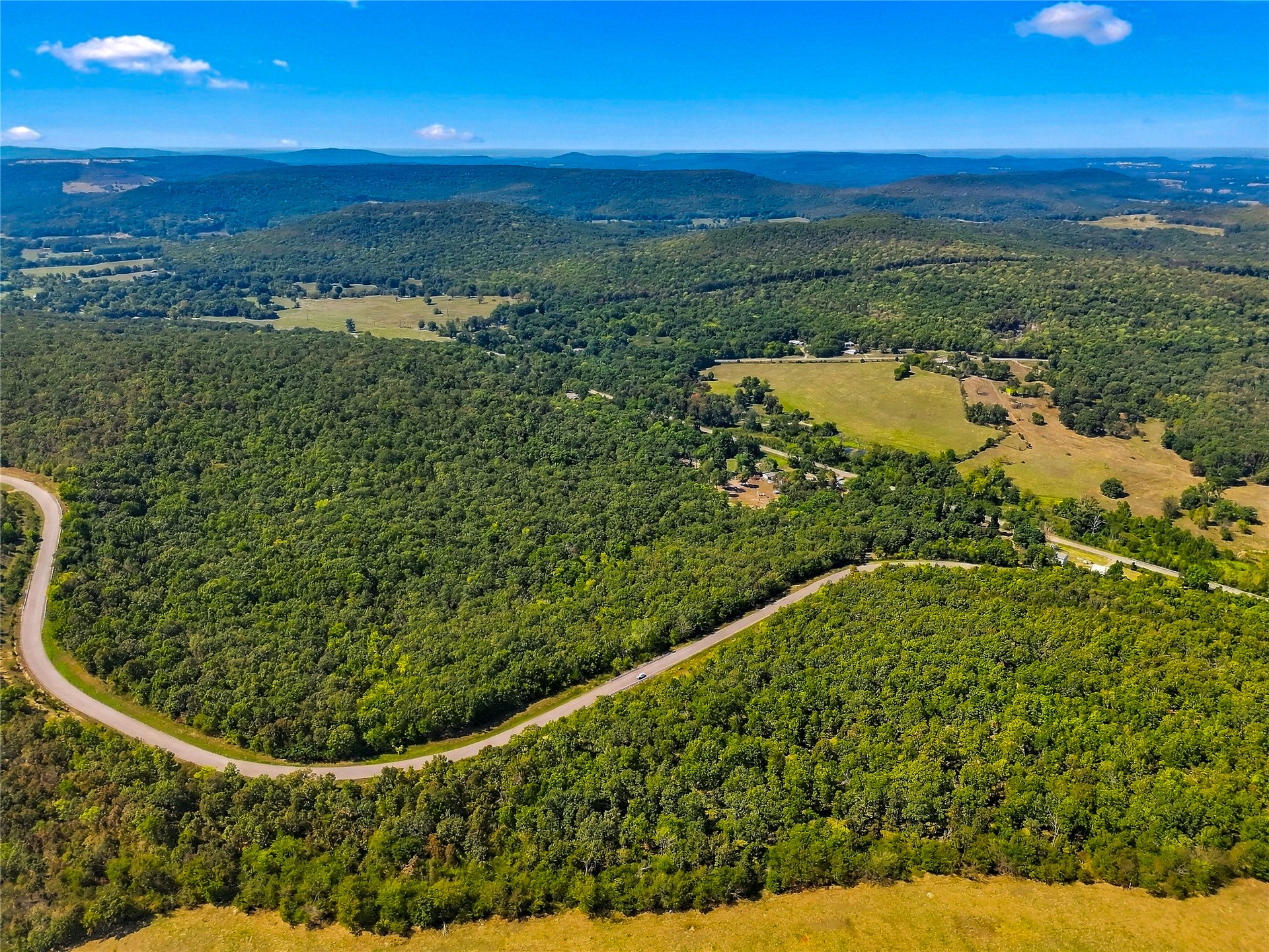 90333 South 4697 Road Stilwell, OK 74960 - Photo 10 of 26 Expansive wooded landscape with a paved road, surrounded by rolling hills and scattered clearings