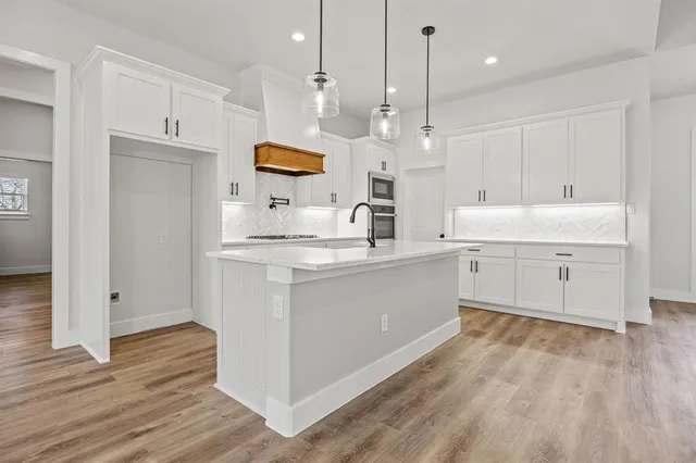 a large white kitchen with a large window a sink and stainless steel appliances