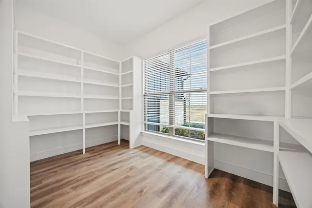 a view of a room with wooden floor a ceiling fan and a window