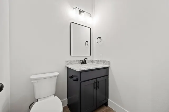 a bathroom with a granite countertop sink toilet and mirror