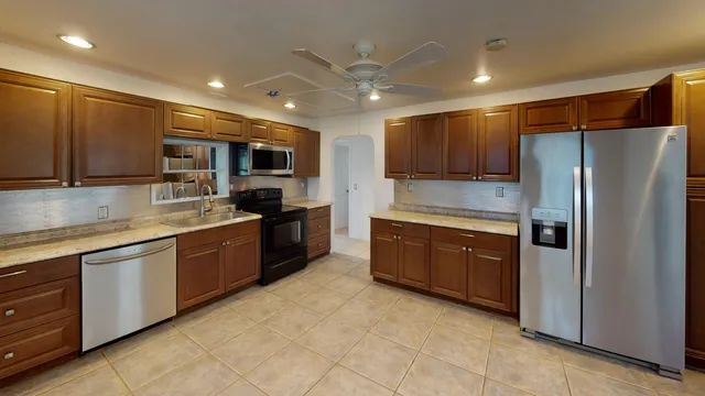 a large kitchen with stainless steel appliances granite countertop a refrigerator and a stove top oven