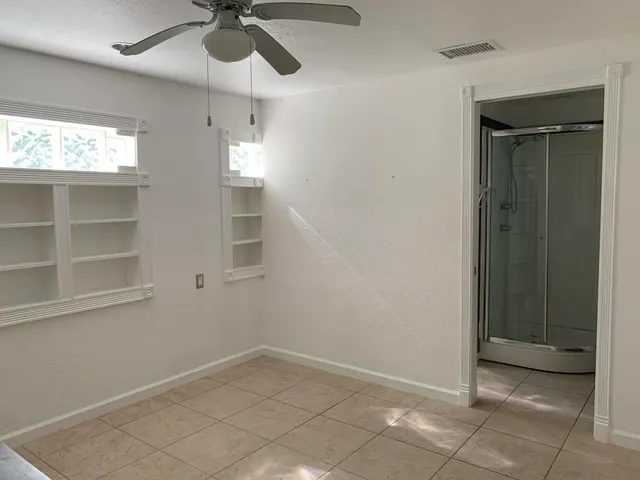 an empty room with windows and fan