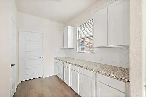 a kitchen with granite countertop white cabinets and a window