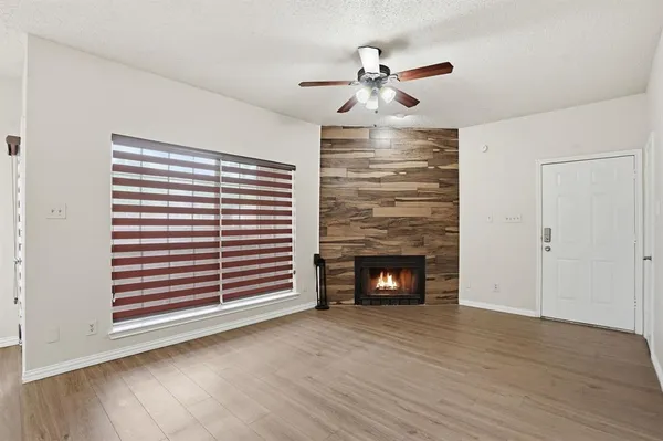 a view of an empty room with wooden floor fireplace and a window