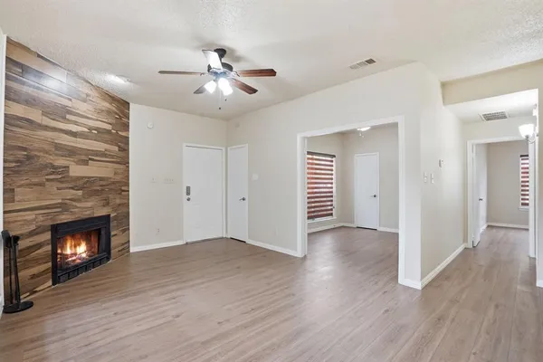 a view of an empty room with wooden floor fireplace and a window
