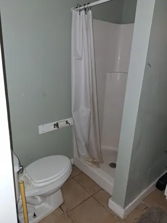 a white toilet sitting next to a shower